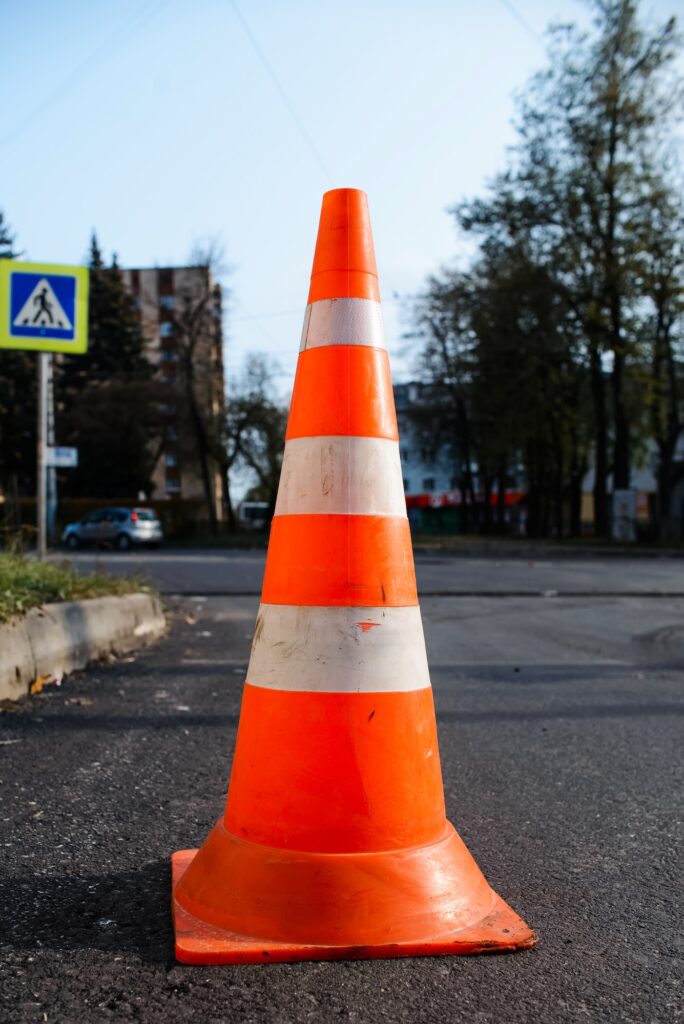 Bright orange traffic cone standing on the road. Vertical photo